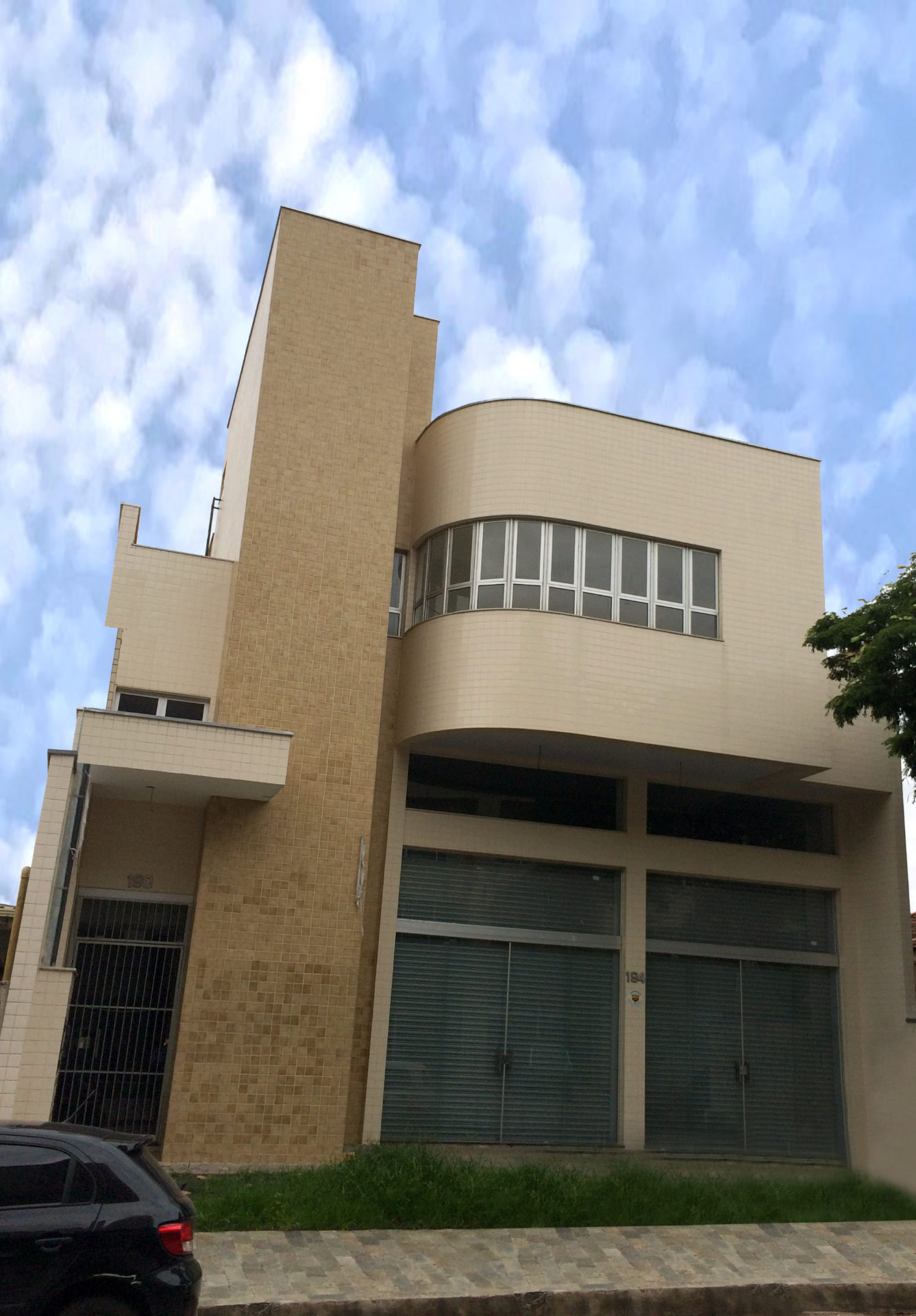 Edifício Jânio com fachada em pastilhas bege, volume curvo e lojas no térreo